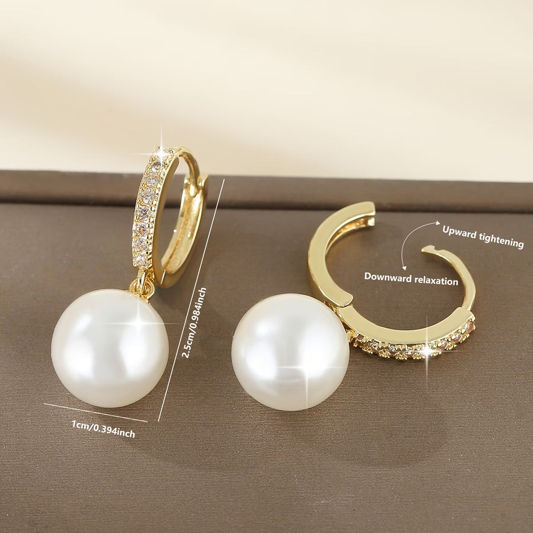 Pair of modern pearl drop earrings laid flat side by side