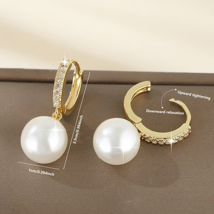 Pair of modern pearl drop earrings laid flat side by side
