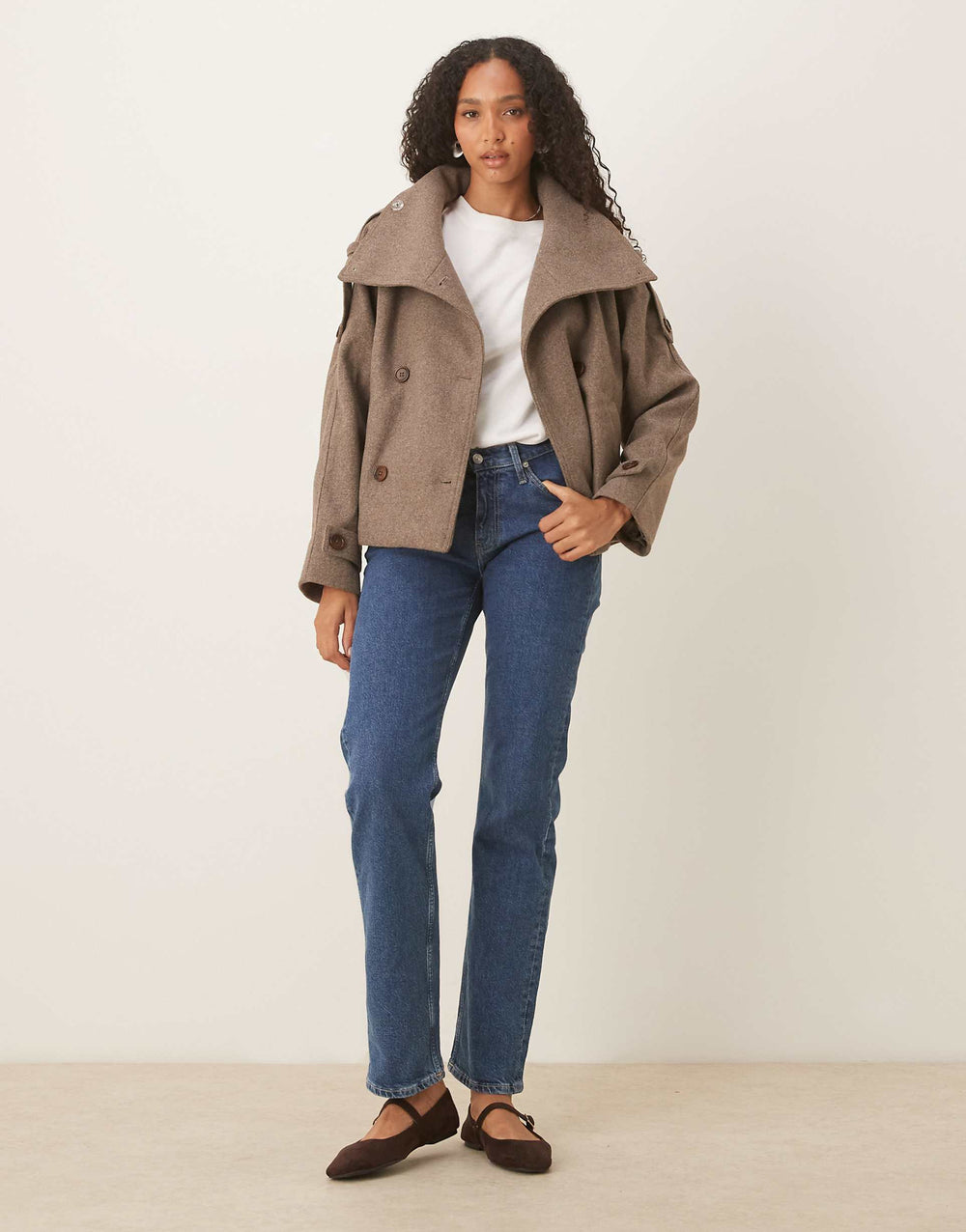 Woman wearing brown wool funnel neck swing coat with blue jeans, full length front view