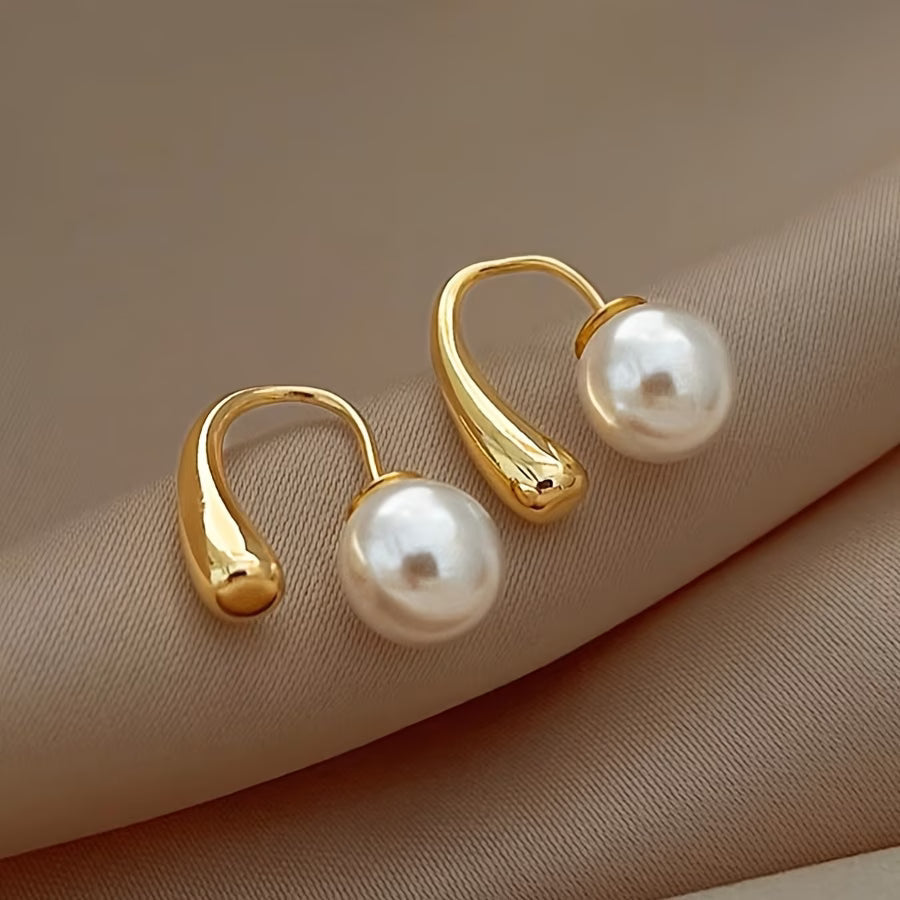 Minimalist arc pearl earrings photographed from an angle