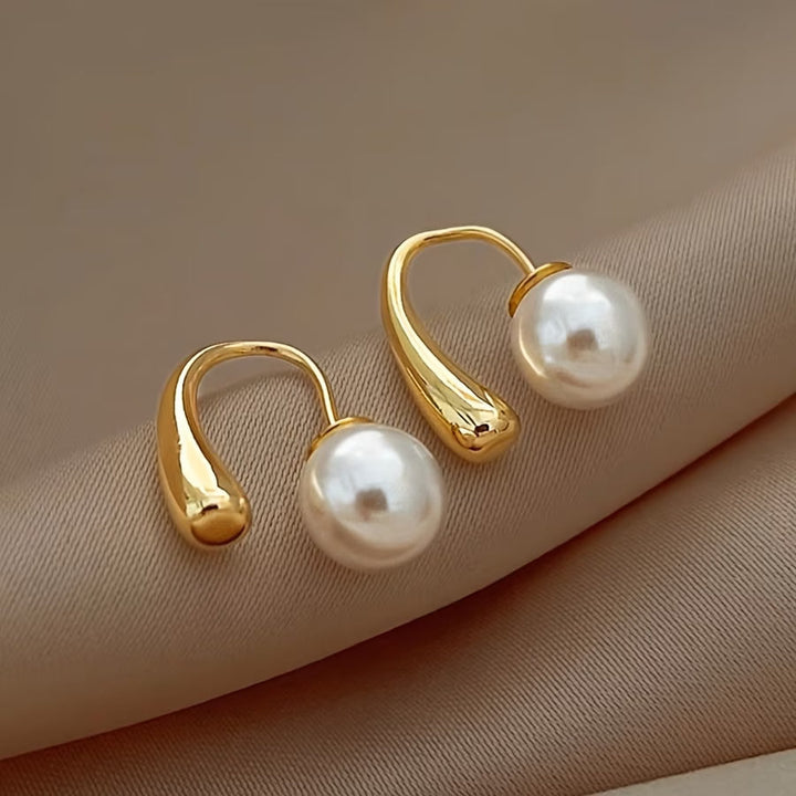 Minimalist arc pearl earrings photographed from an angle