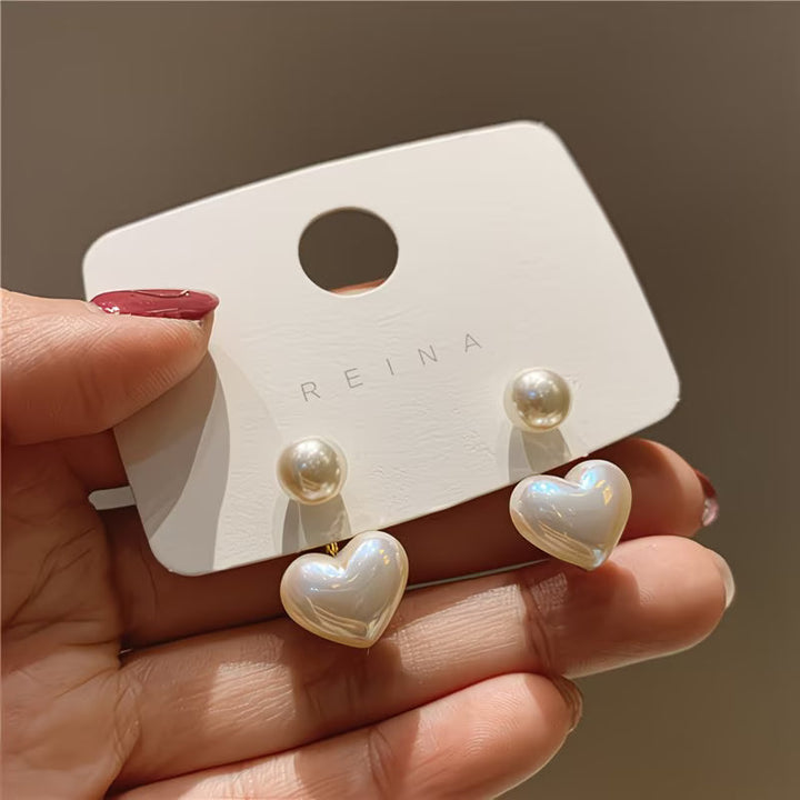 Double pearl heart earrings shown on a white background