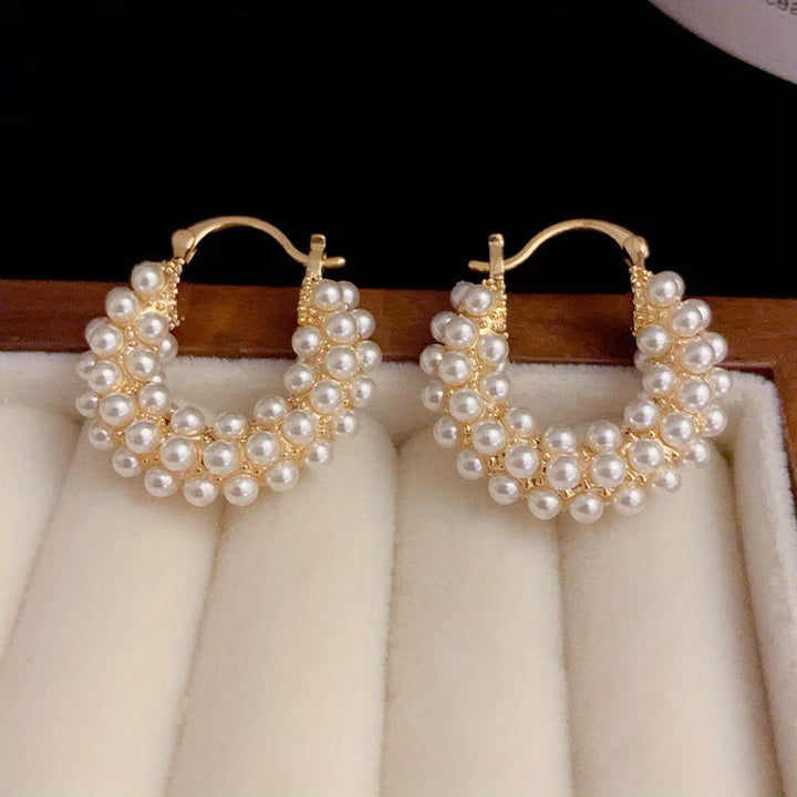 Layered pearl hoop earrings on a plain white background