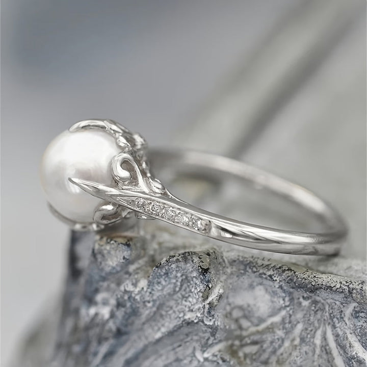 Pearl and crystal ring shown worn on a hand