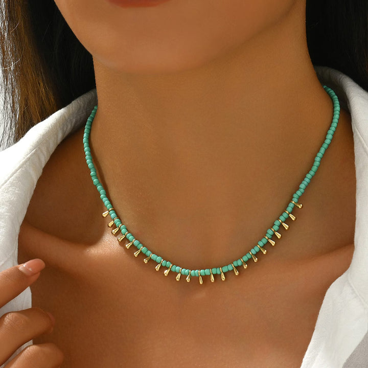 Minimal turquoise and gold-tone necklace laid flat on a plain background