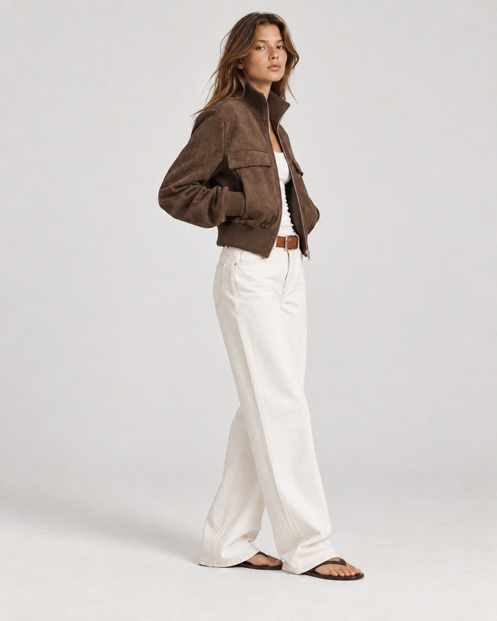 Side view of dark brown cropped suede bomber jacket showing ribbed cuffs and hem