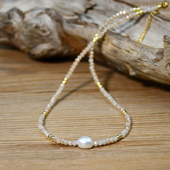 Minimal beach pearl necklace laid flat on a light background