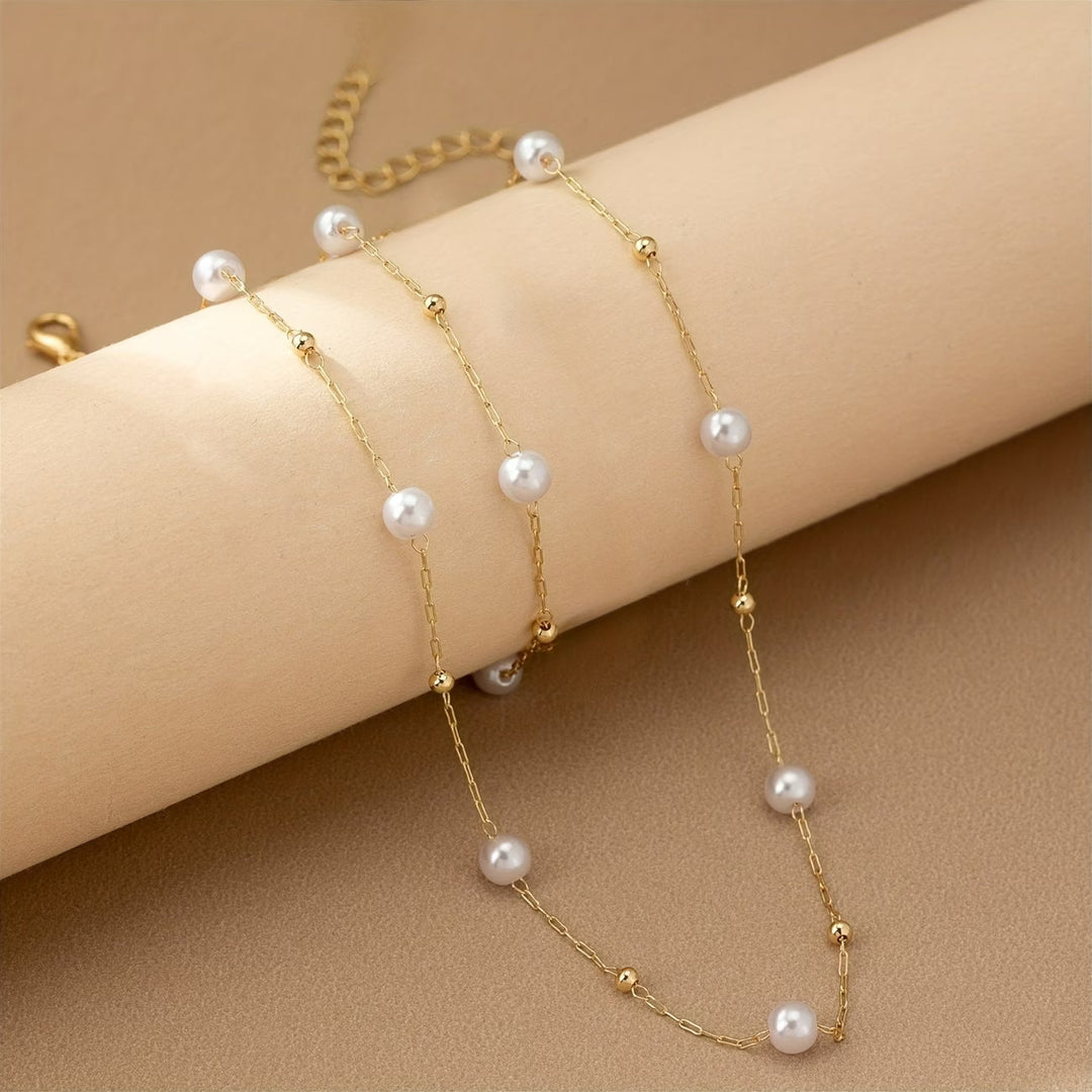 Dainty pearl chain necklace laid flat on a plain background