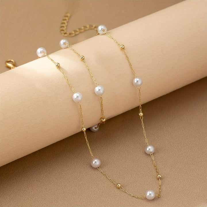 Dainty pearl chain necklace laid flat on a plain background