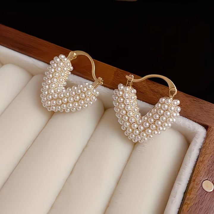 V-shaped pearl earrings shown on a white background