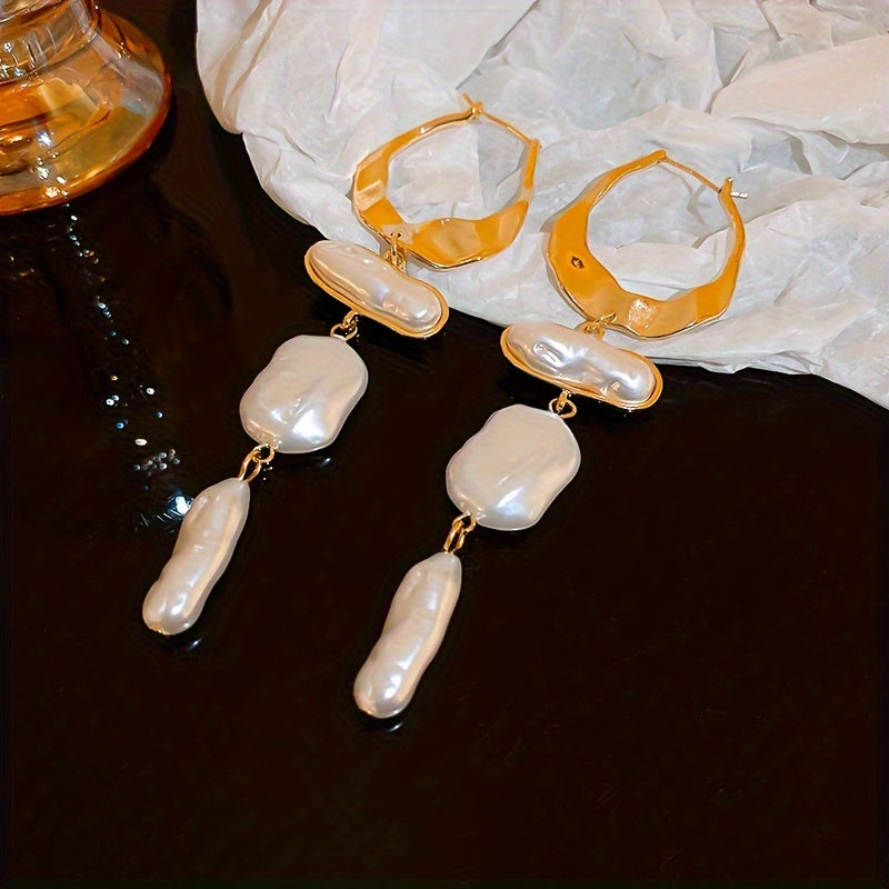 Pearl hoop earrings laid flat next to draped fabric