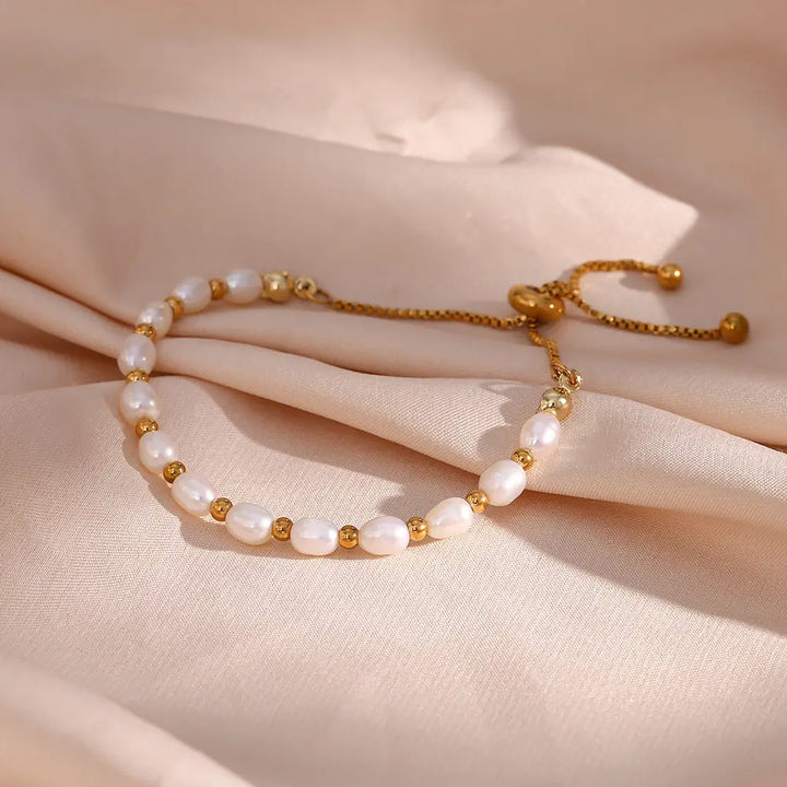 Pearl and gold-tone bracelet laid flat on a white surface