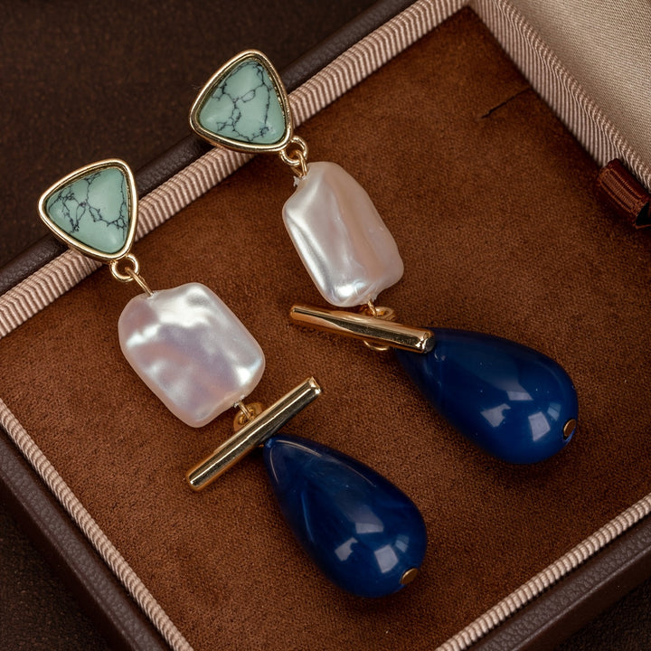 Turquoise pearl earrings worn in the ear to show the drop