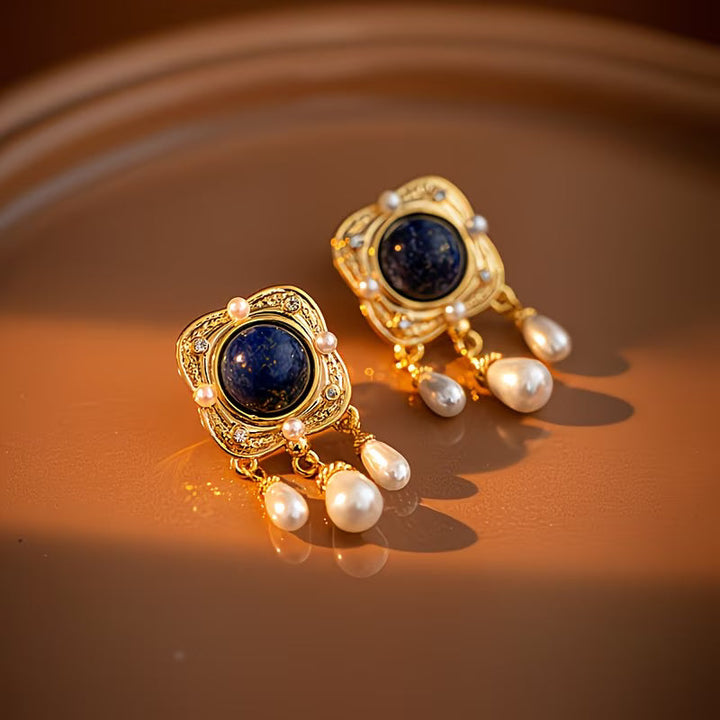 Pair of chandelier earrings laid side by side on fabric