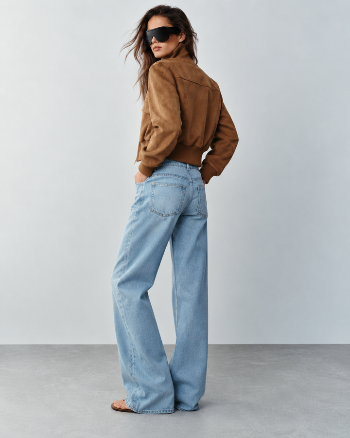 Back view of tan suede cropped bomber jacket styled with light wash denim jeans