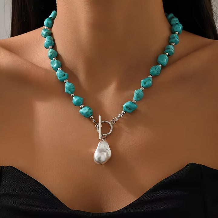 Turquoise and pearl silver necklace laid flat on a neutral backdrop