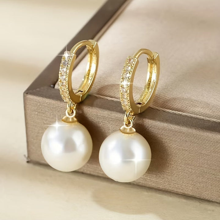 Modern pearl drop earrings displayed standing upright on a stand