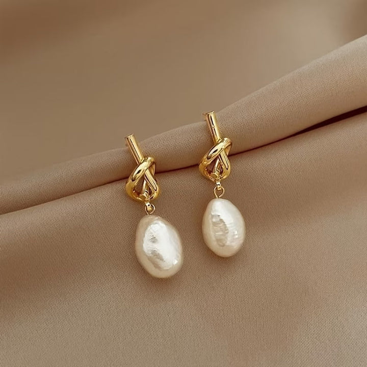 Knotted pearl earrings displayed on a plain background
