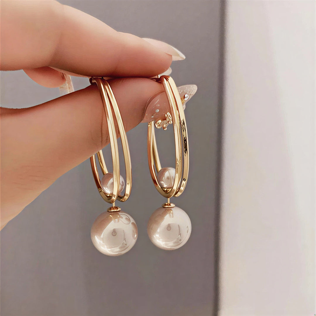 Vintage charm pearl earrings laid flat showing the ornate setting
