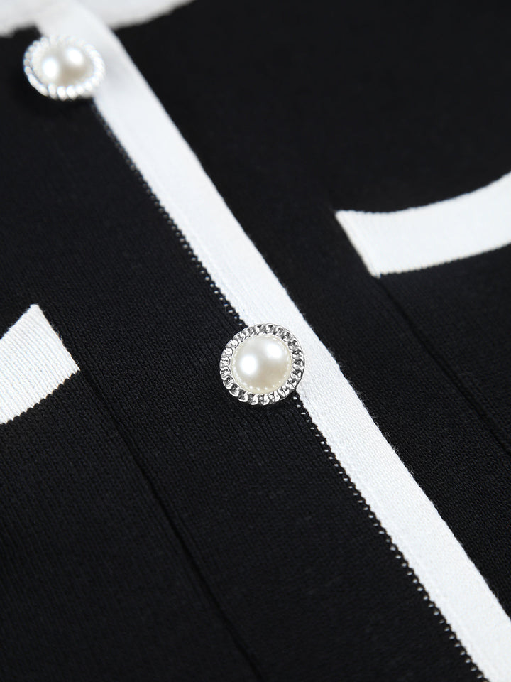Macro of the crystal set pearl buttons and white ribbon trim on the black knit dress