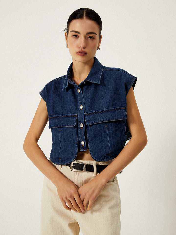 Indigo denim vest worn buttoned with arms down, cropped boxy silhouette