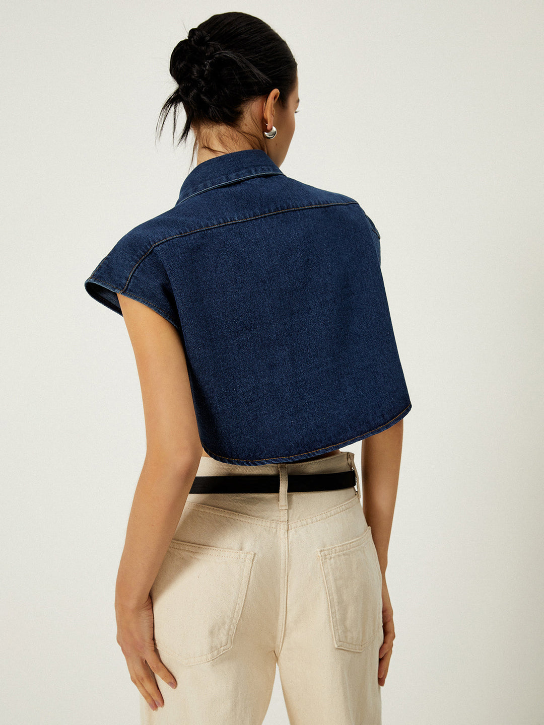 Back view of dark denim sleeveless vest showing cap shoulders and cropped length