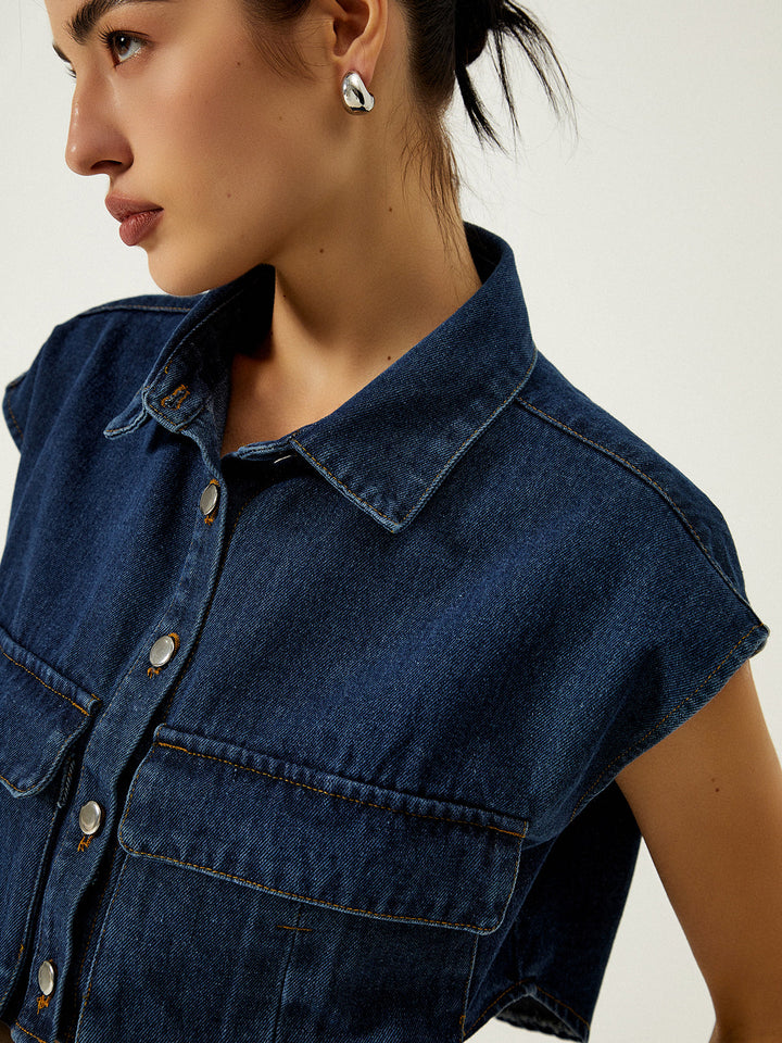 Close-up of turn-down collar, silver buttons and chest patch pocket on denim vest