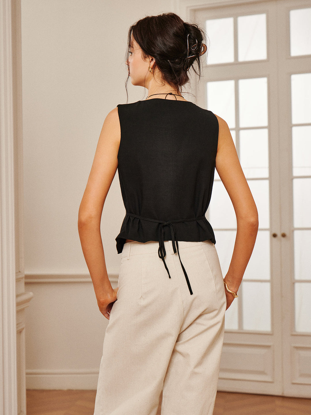 Back view of black linen vest showing gathered peplum hem with drawstring tie