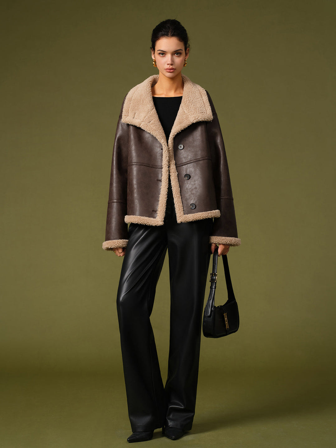 Full length shot of brown aviator jacket styled with black leather trousers and a shoulder bag