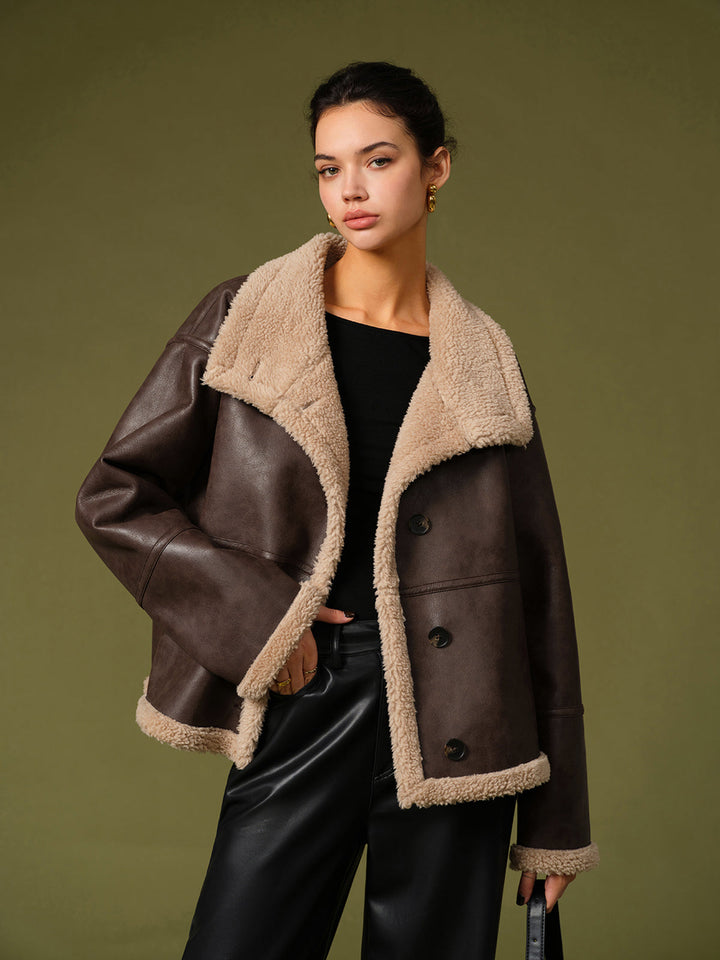 Model wearing an oversized dark brown shearling lined faux leather jacket with cream teddy trim