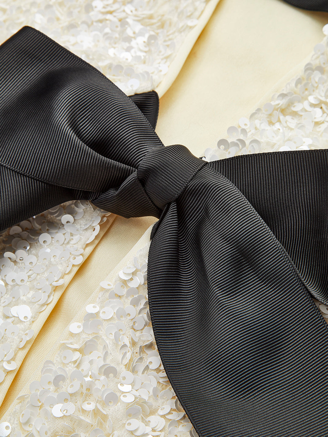 Close-up of the black satin bow against the iridescent cream sequin fabric