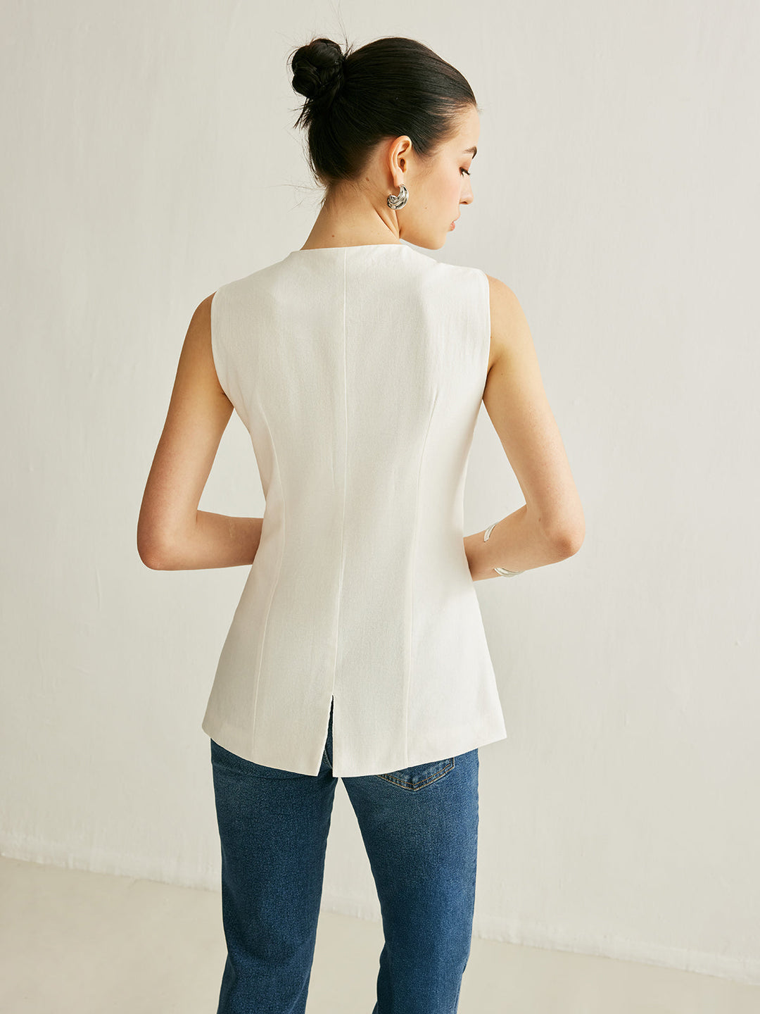 Back view of the white linen vest showing the centre back slit at the hem