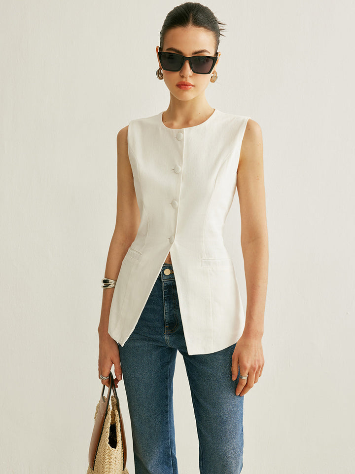 Model in sunglasses wearing the white sleeveless vest over denim with a raffia bag