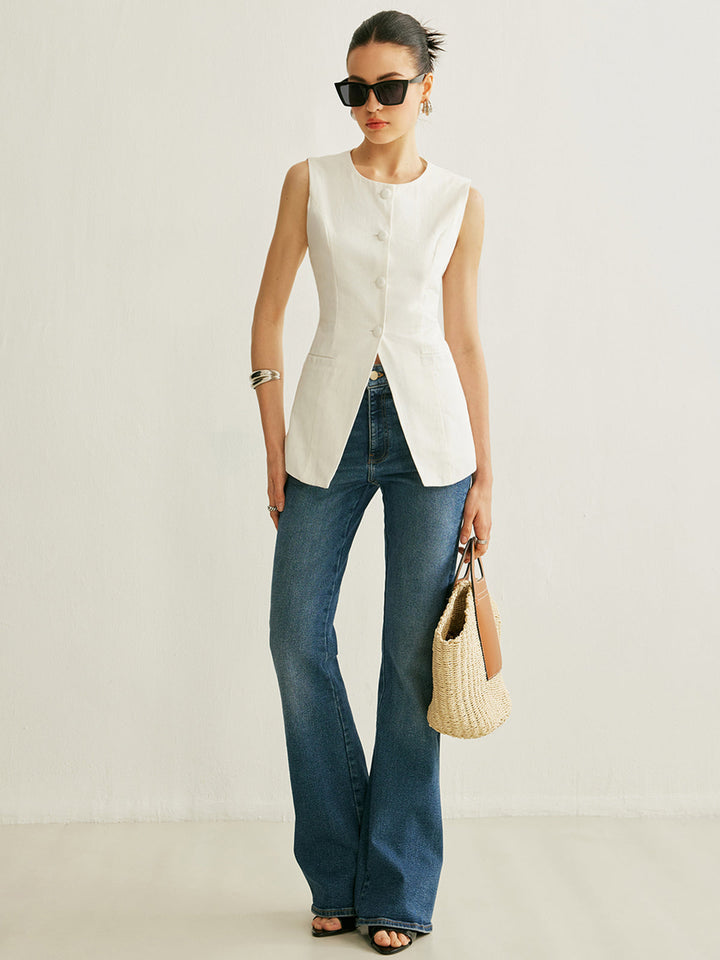 Full-length look: white longline vest with flared jeans and a woven straw handbag