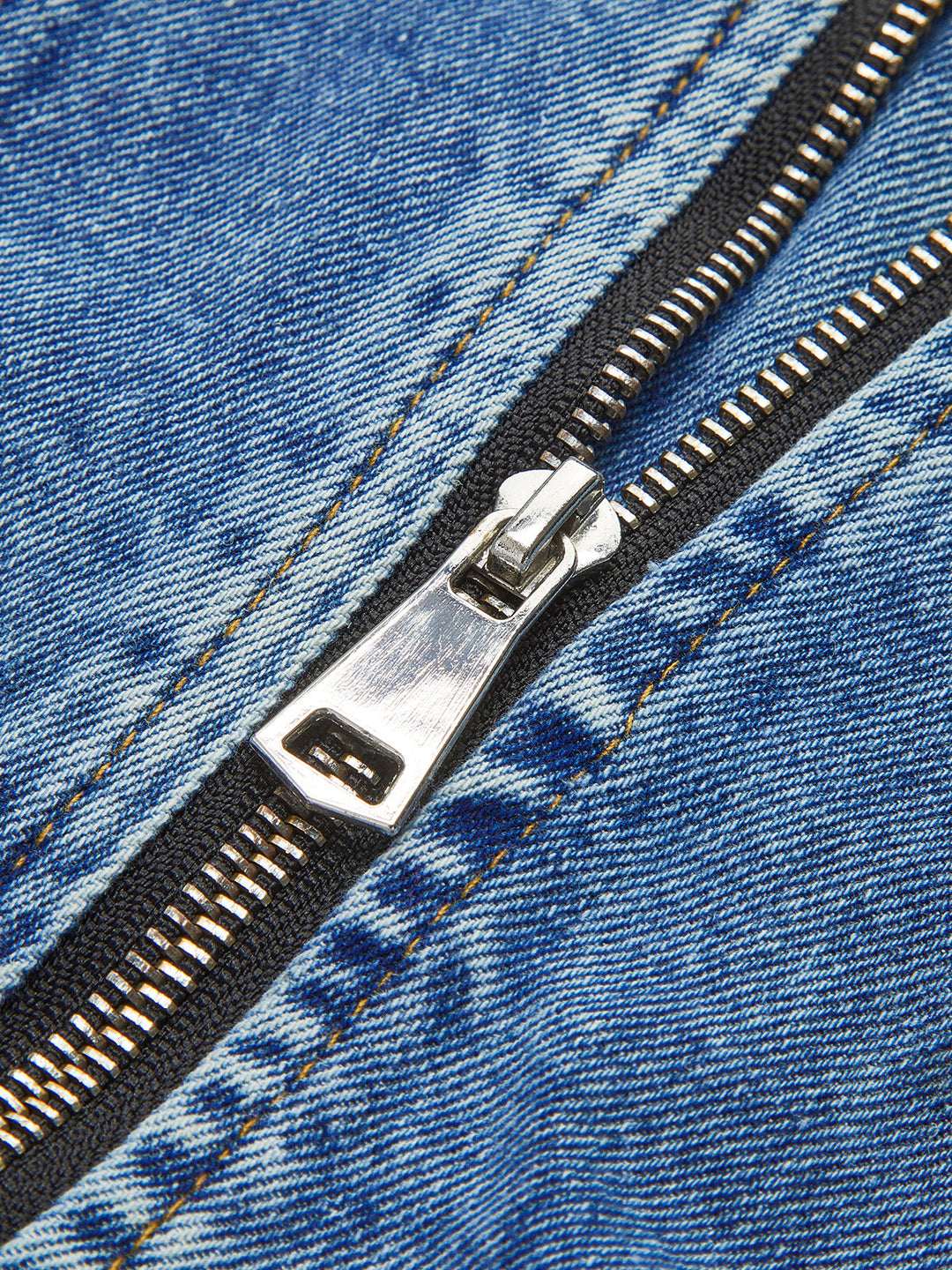 Close-up of silver zip pull on the blue denim panel of a black crop jacket