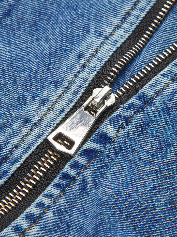 Close-up of silver zip pull on the blue denim panel of a black crop jacket