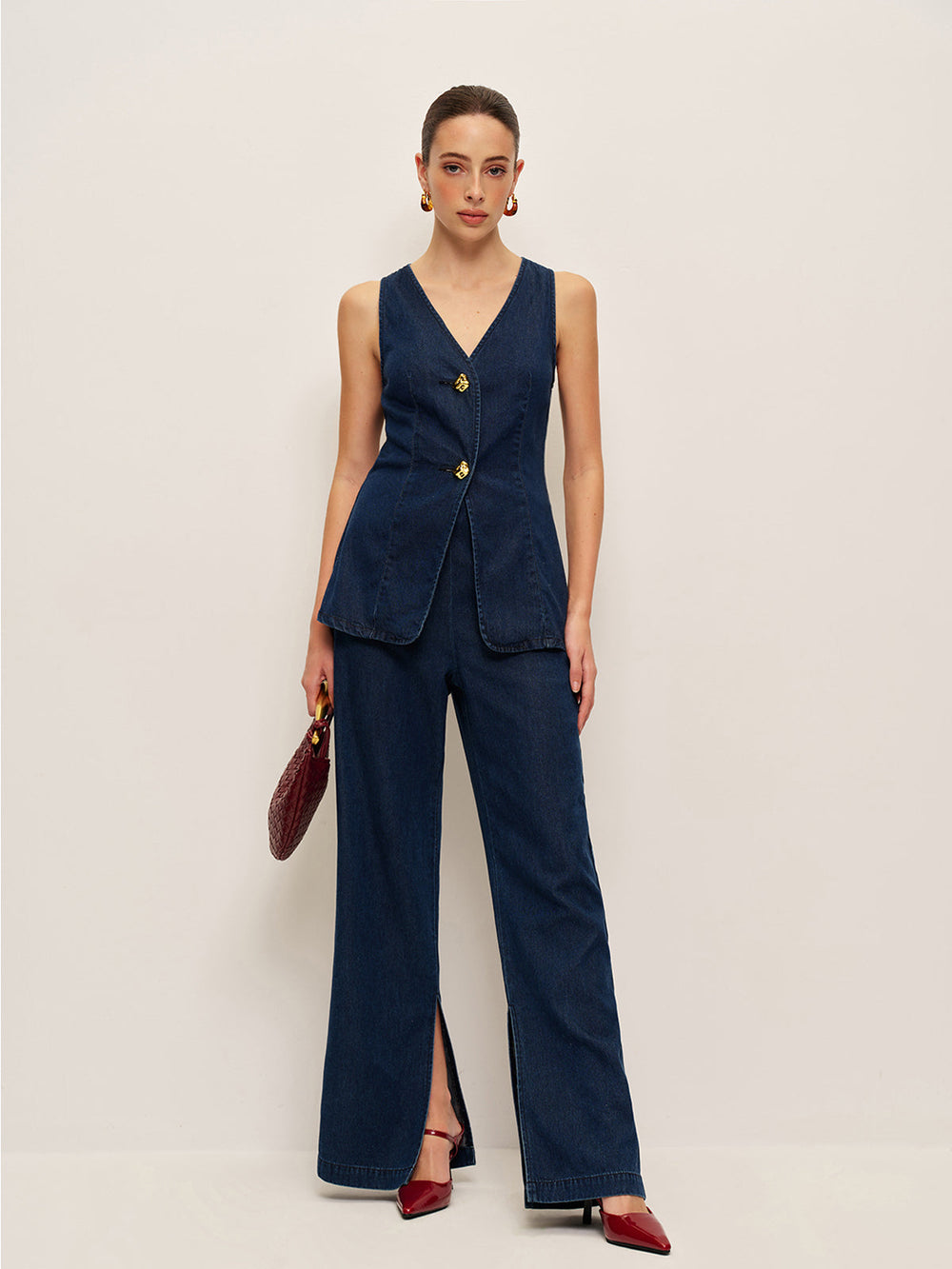 Side view of denim vest and trouser suit with burgundy shoulder bag