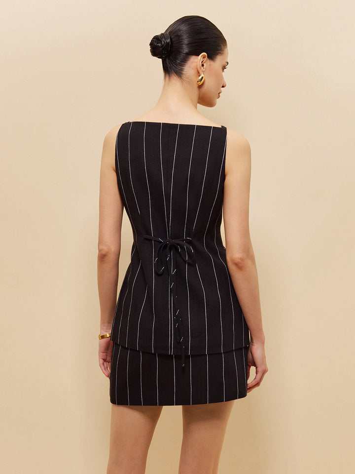 Achterkant zwart krijtstreep vest met strikbandje in de taille over mini rok