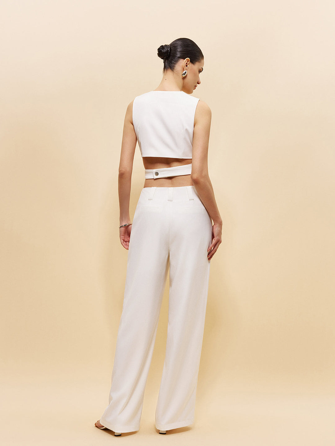 Back view of the white cropped sleeveless top showing the open midriff band and ring