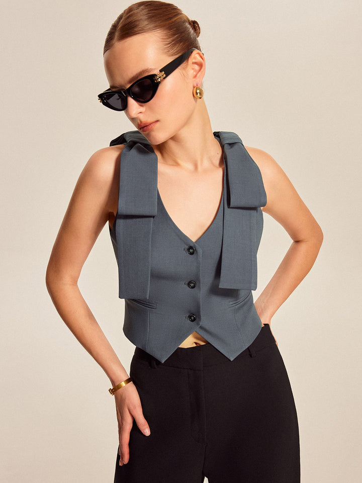 Slate blue bow shoulder vest with V-neck worn over black wide-leg trousers