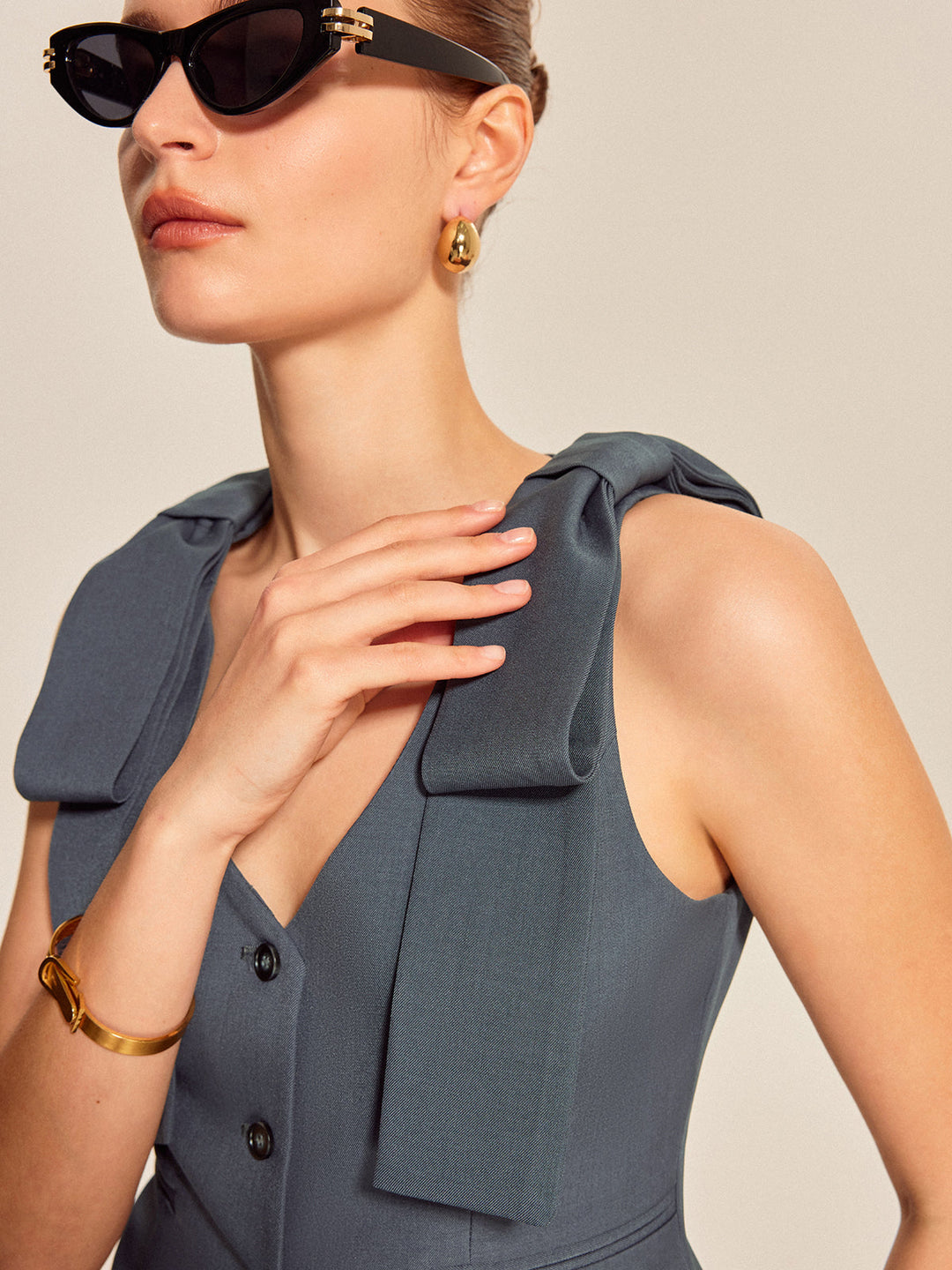 Close-up of oversized fabric bow detail on the shoulder of grey-blue vest