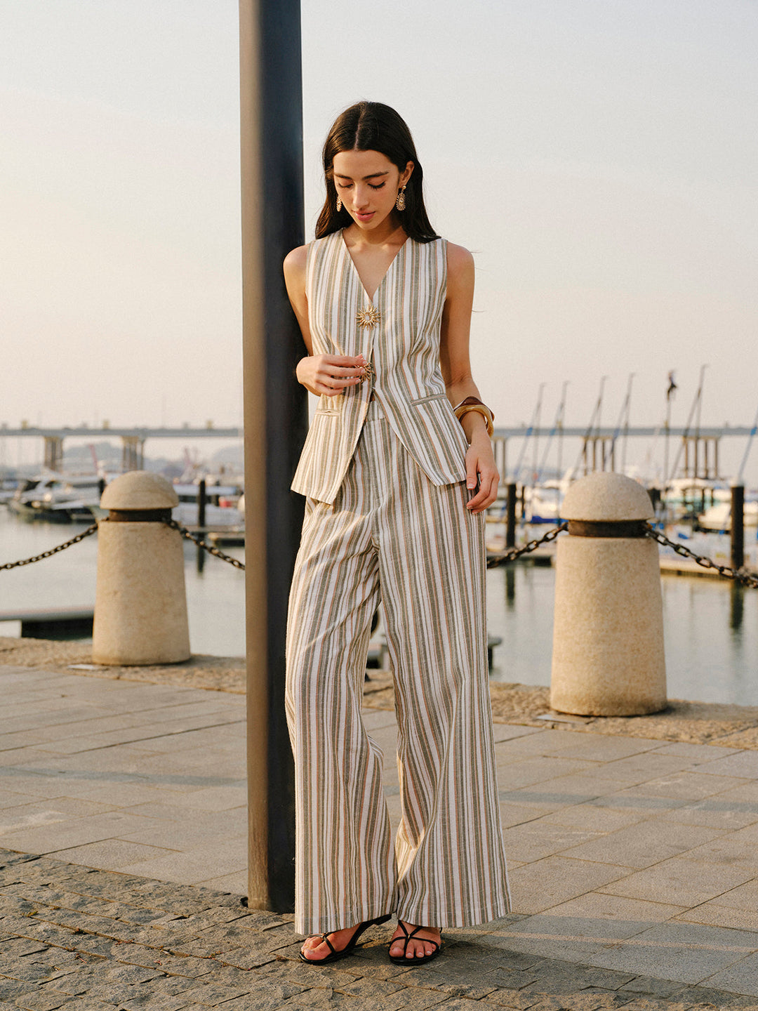 Model adjusting striped linen vest with asymmetric hem and welt pockets