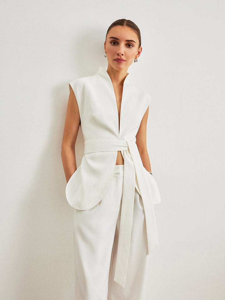 Front view of white cap shoulder belted vest showing patch pockets and plunging neckline