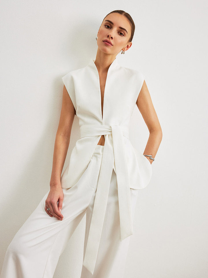 Side view of the ivory belted peplum top with crisp tailored shoulders