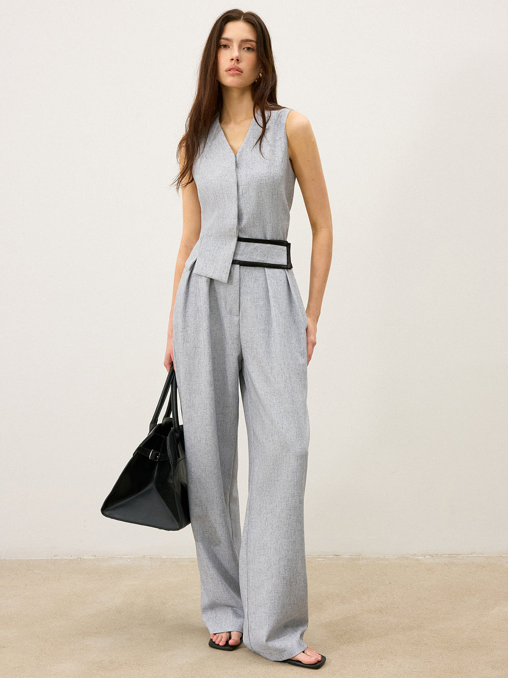 Full-length grey vest and trouser suit worn with a black tote bag