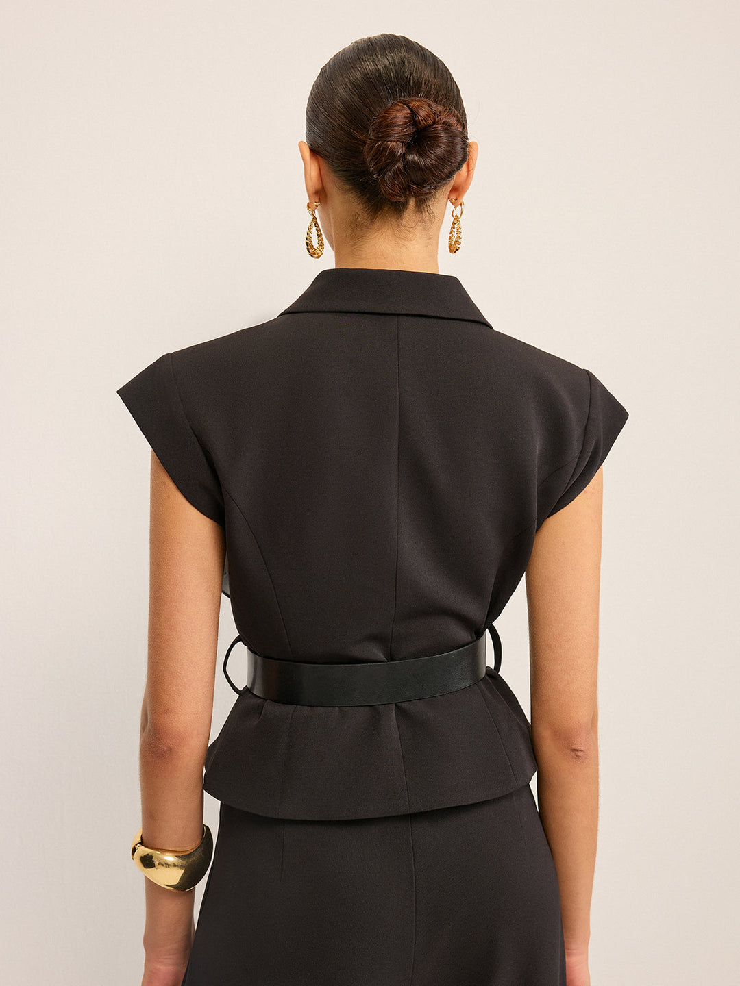 Back view of the black peplum vest with belt loops and flared back hem