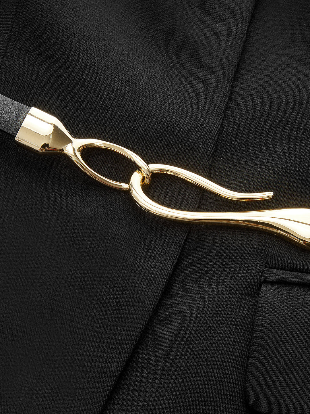 Close-up of the gold twisted hook buckle on the belt of the black sleeveless blazer vest