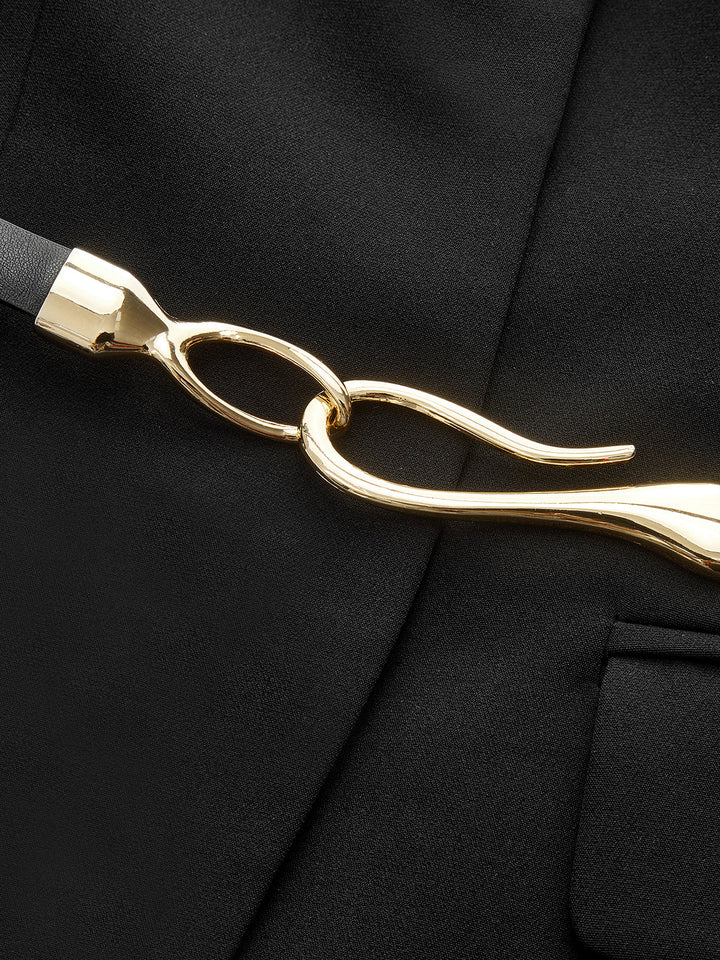 Close-up of the gold twisted hook buckle on the belt of the black sleeveless blazer vest