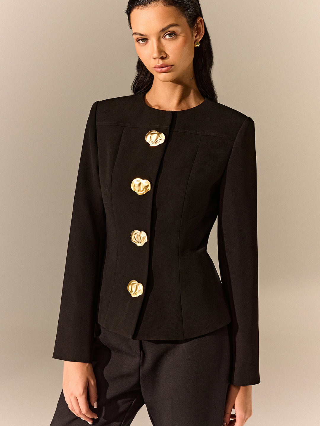 Front view of a black round neck blazer with a vertical row of molten gold buttons