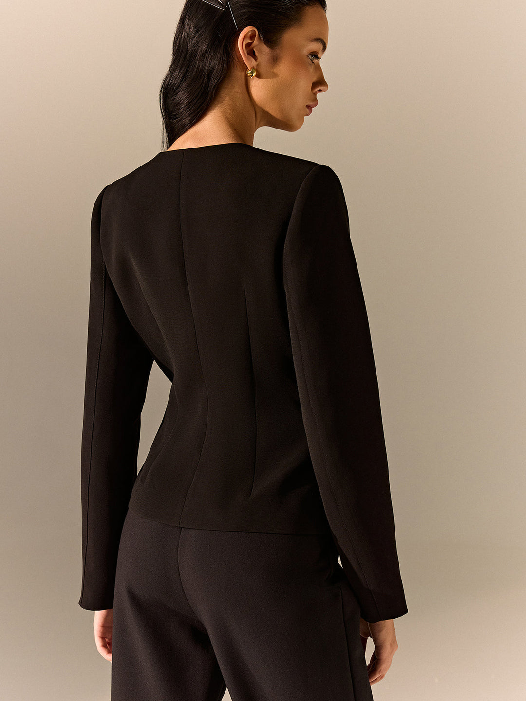 Back view of a black tailored blazer showing the sculpted shoulders and fitted back seams